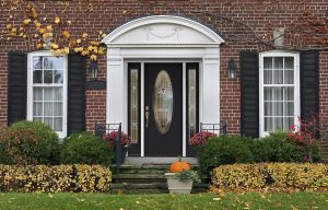 Glass-paneled front door with sidelights on brick colonial-style home