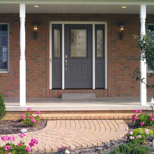 Blue-gray door with glass panel and sidelights on brick home with extended porch area