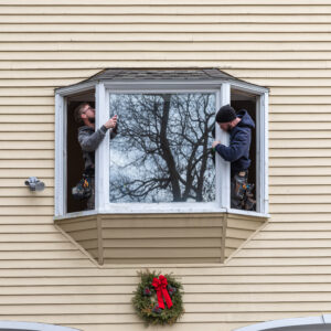 window installers from 12 Penny Exteriors removing a pane of glass from a window